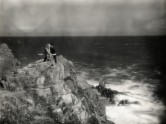 b/w photo of a woman and man on cliff by the ocean