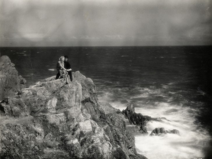 b/w photo of a woman and man on cliff by the oceanalr
