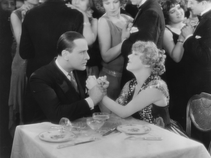 b/w photo of a woman and man holding hands at a table in a dance clubalr