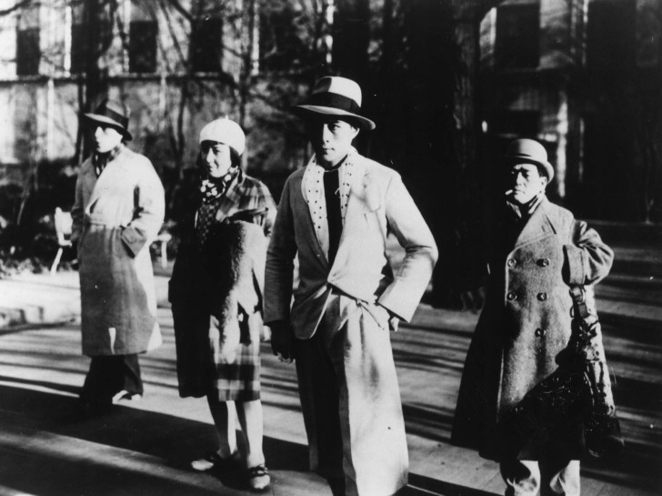 three men and two women in 30s-era wear stand in the street with serious expressionsalr