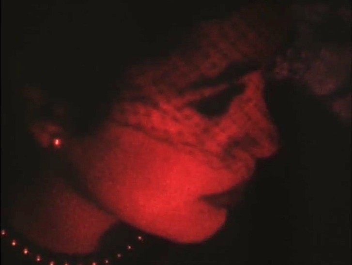 an evocative red-tinged image of a woman's face turned to the side, wearing a veilalr