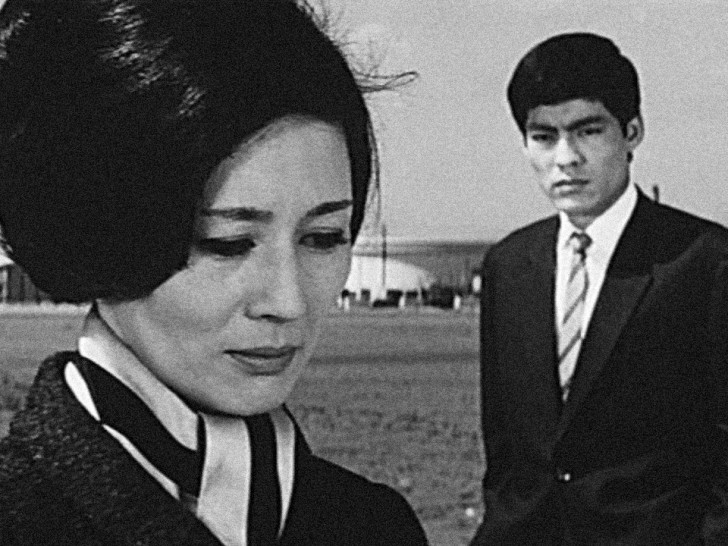 Tsukasa Yoko in the foreground, looking upset, while Ozawa Eitaro approaches heralr