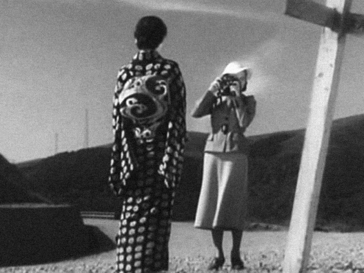 the back of a woman in a kimono faces us while the woman in front of her, in western dress, takes her picturealr