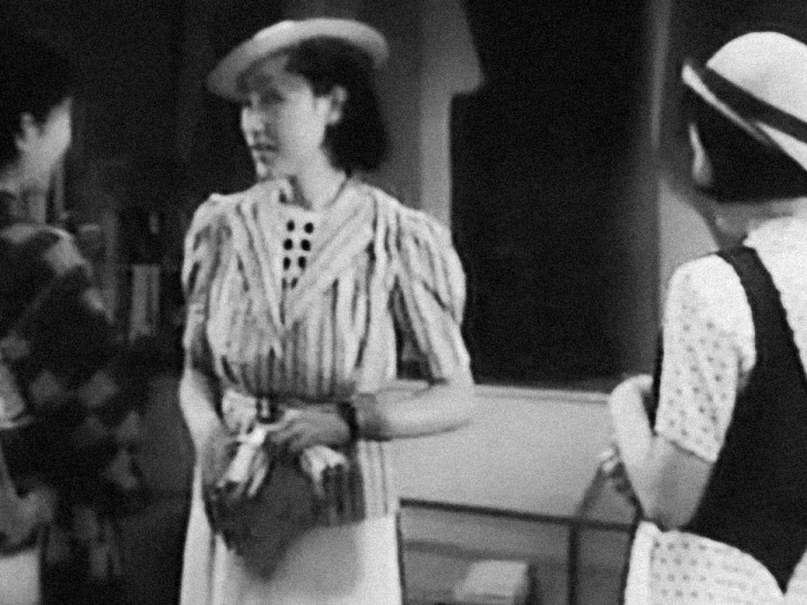 two Japanese women talk excitedly to a third, all in western dressalr