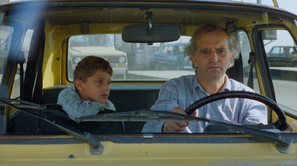young boy in the passenger seat next to older man driving a caralr