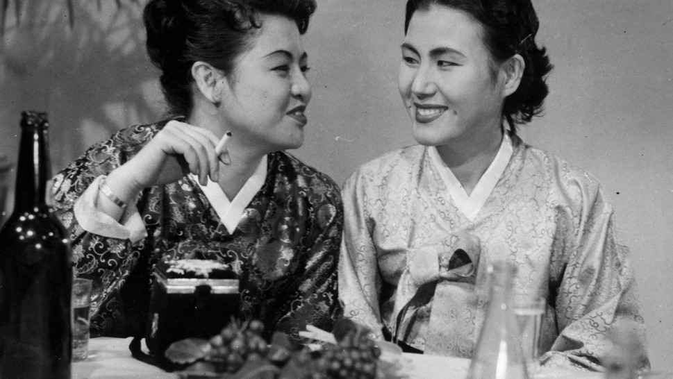 two Japanese women in traditional dress smiling and talking while diningalr
