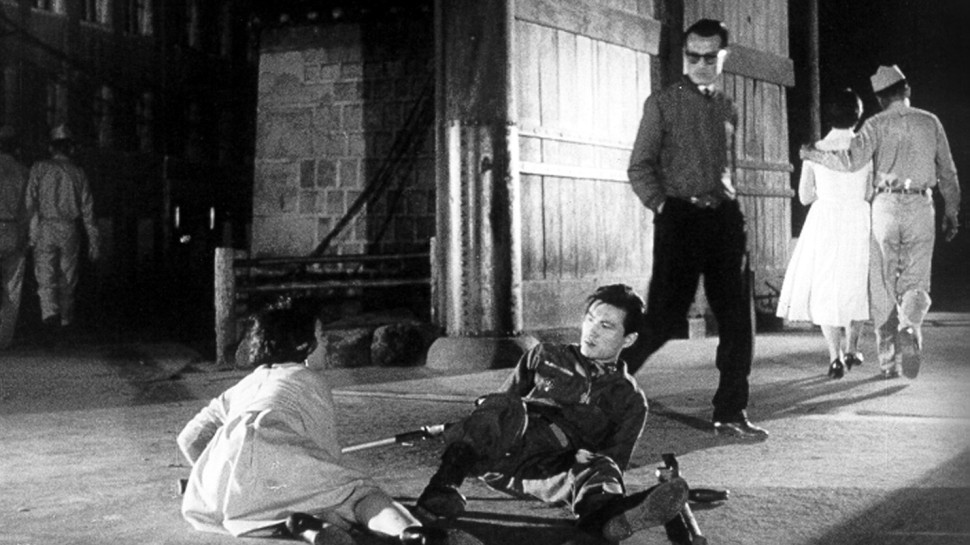 a Korean man and woman on the ground, after an apparent altercation, while another man looks on and a couple walks awayalr
