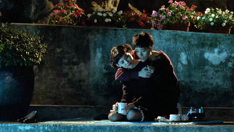 a teenage Taiwanese boy and girl drink coffee in a garden at nightalr