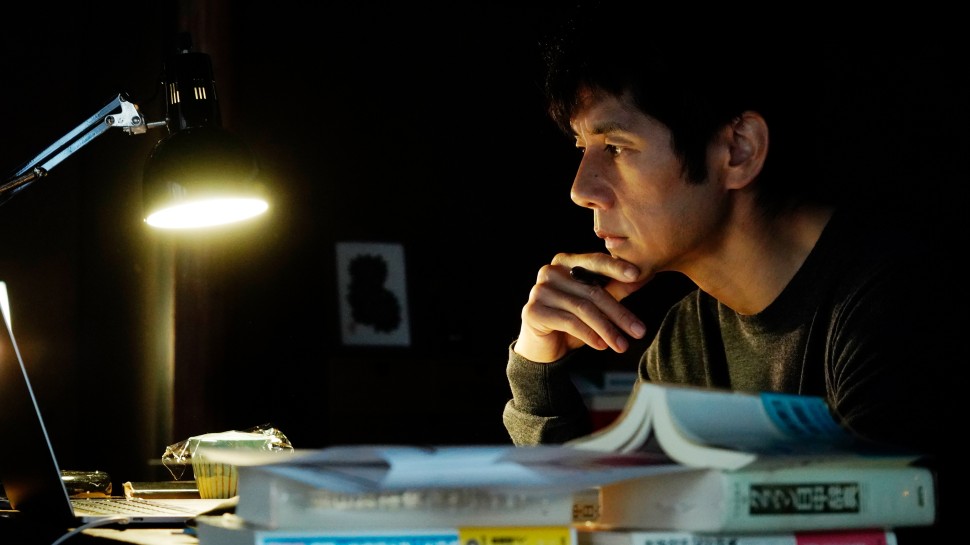 Nishijima Hidetoshi works at a desk with many books on it at nightalr