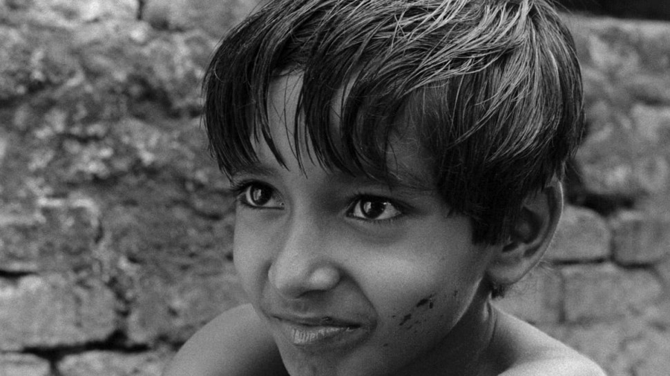 a close up of 8-year-old Subir Banerjee, with a dirty face and smiling eyesalr