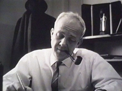 Humphrey Leynse at his desk, smoking a pipe