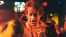 man in a disco talking and holding cigarette