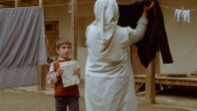 young boy talking to a woman hanging laundry