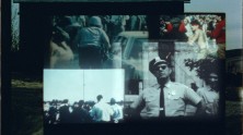 A quadruple projection of images on a barn, including one of a police officer and others of crowds