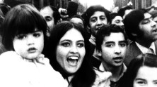 a close-up of a few Chileans in a crowd, including a smiling woman with her child, all shouting