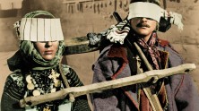 Larisa Kadochnikova and Ivan Mikolaychuk blindfolded and bound to one another with a wooden contraption