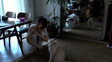 Kim Minhee sits on the floor with a Persian cat and both are reflected in a mirror