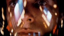 close-up of a white male astronaut with many lights reflecting on his face shield