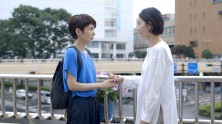 two Japanese women speak to one another on a bridge