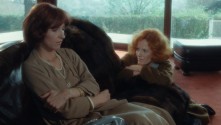 Noëlle Châtelet sits despondently while Delphine Seyrig kneels beside her