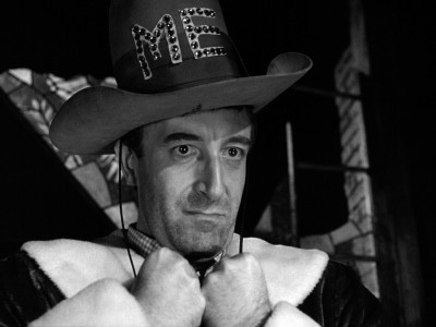 Peter Sellers wearing a large hat with "ME" embroidered on it, and gripping a Pilgrim-like collar